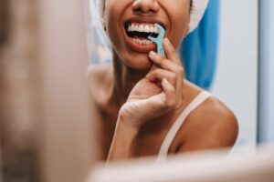 Woman looking in mirror flossing her teeth