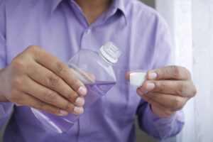 Woman in purple shirt pouring mouthwash into cap.