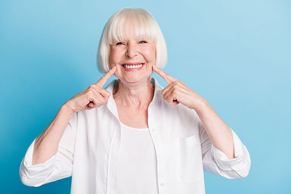 An older woman shows off her healthy smile after visiting a dentist that specializes in treatment of older patients.