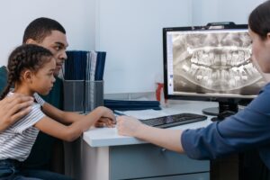 Parent and child reviewing dental x-ray with dentist.