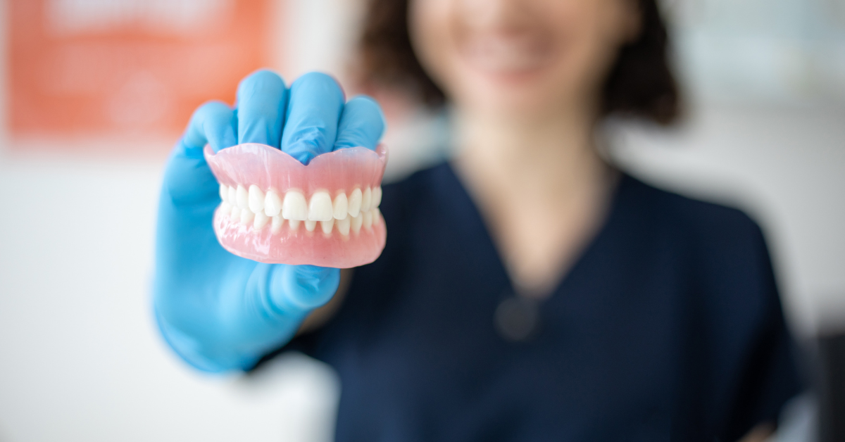 dental hygienist in a dentist's office presenting a new set of affordable dentures to a patient