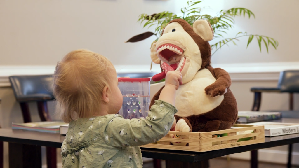 A child brushes the teeth of a stuffed monkey used to teach good oral hygiene in the Midlothian office of a family dentist.