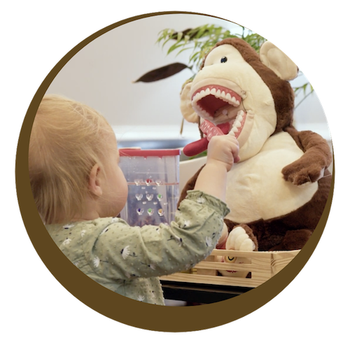 child brushing the teeth of a stuffed monkey